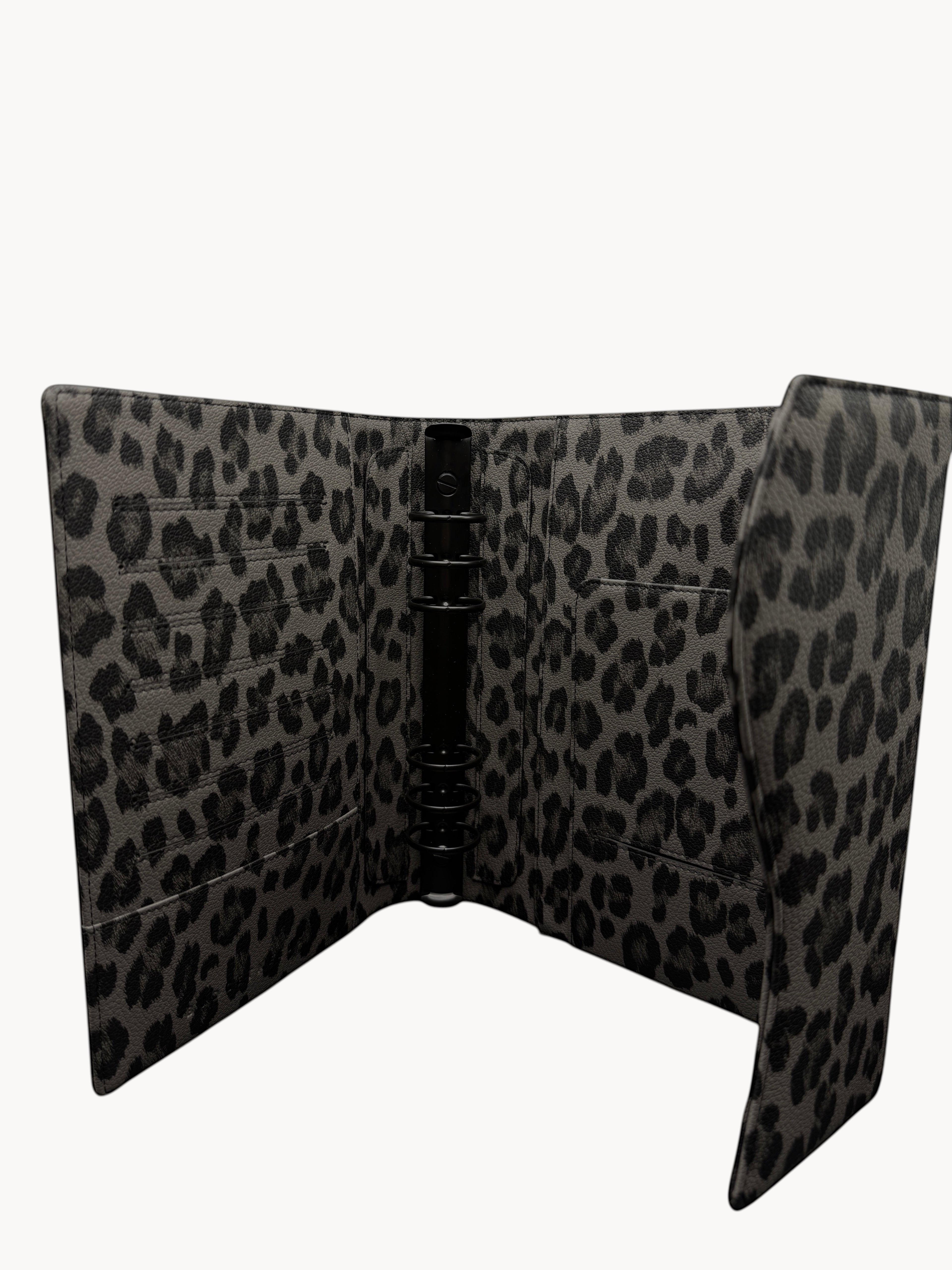 BUDGETNEEDS ™ A5 FlapLine ring binder in a grey and black leopard print pattern with a black metal ring mechanism.