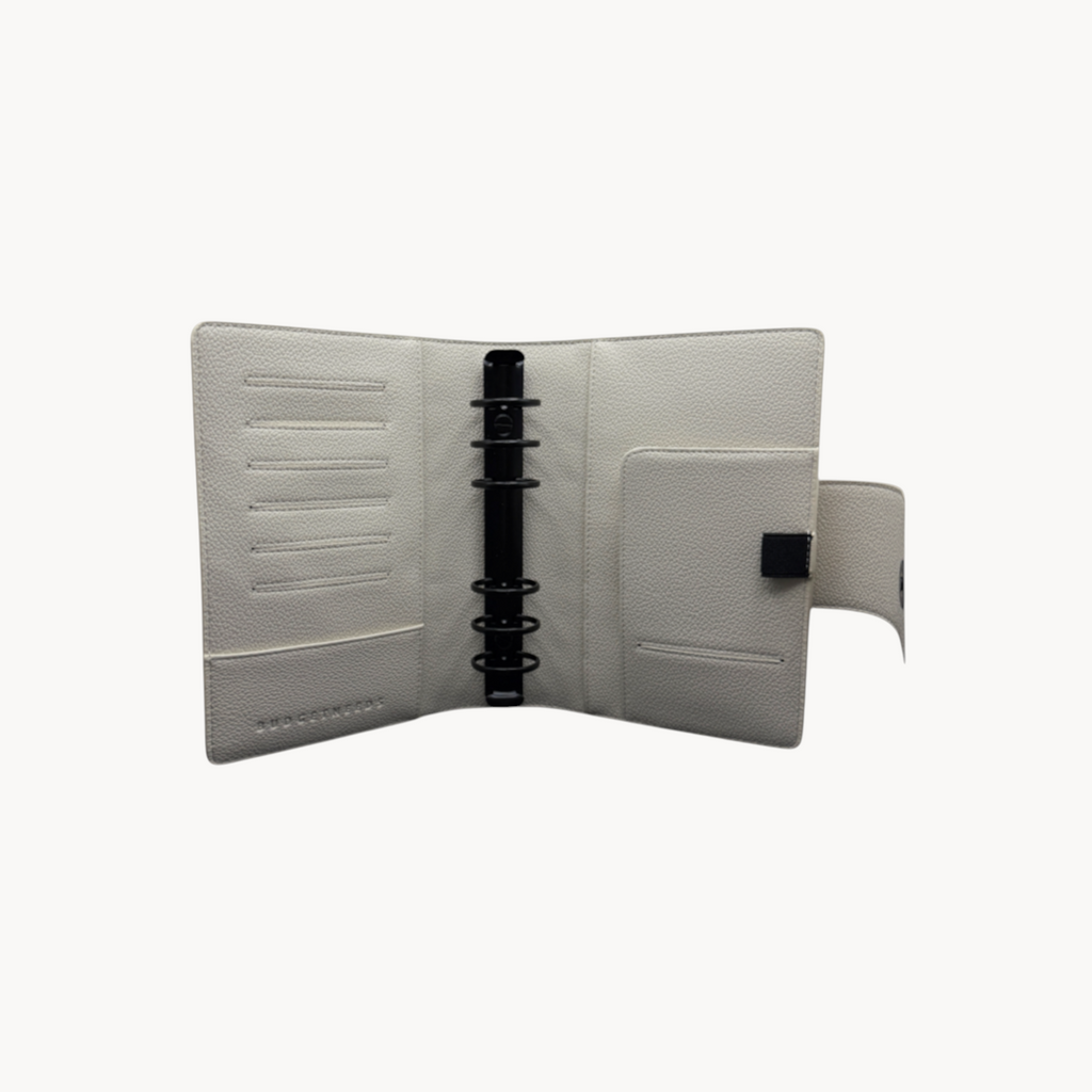 BUDGETNEEDS ™ A6 MiniFlap ring binder in cream with matte black hardware, pen holder, and magnetic closure.